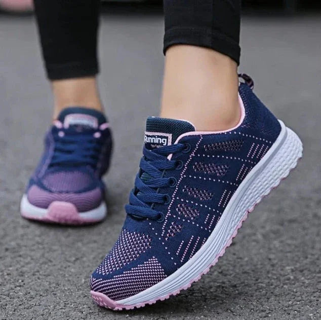 Woman wearing navy blue and pink athletic running shoes with white sole on pavement