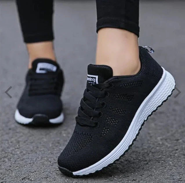 Black athletic running shoes with white soles, worn on pavement.