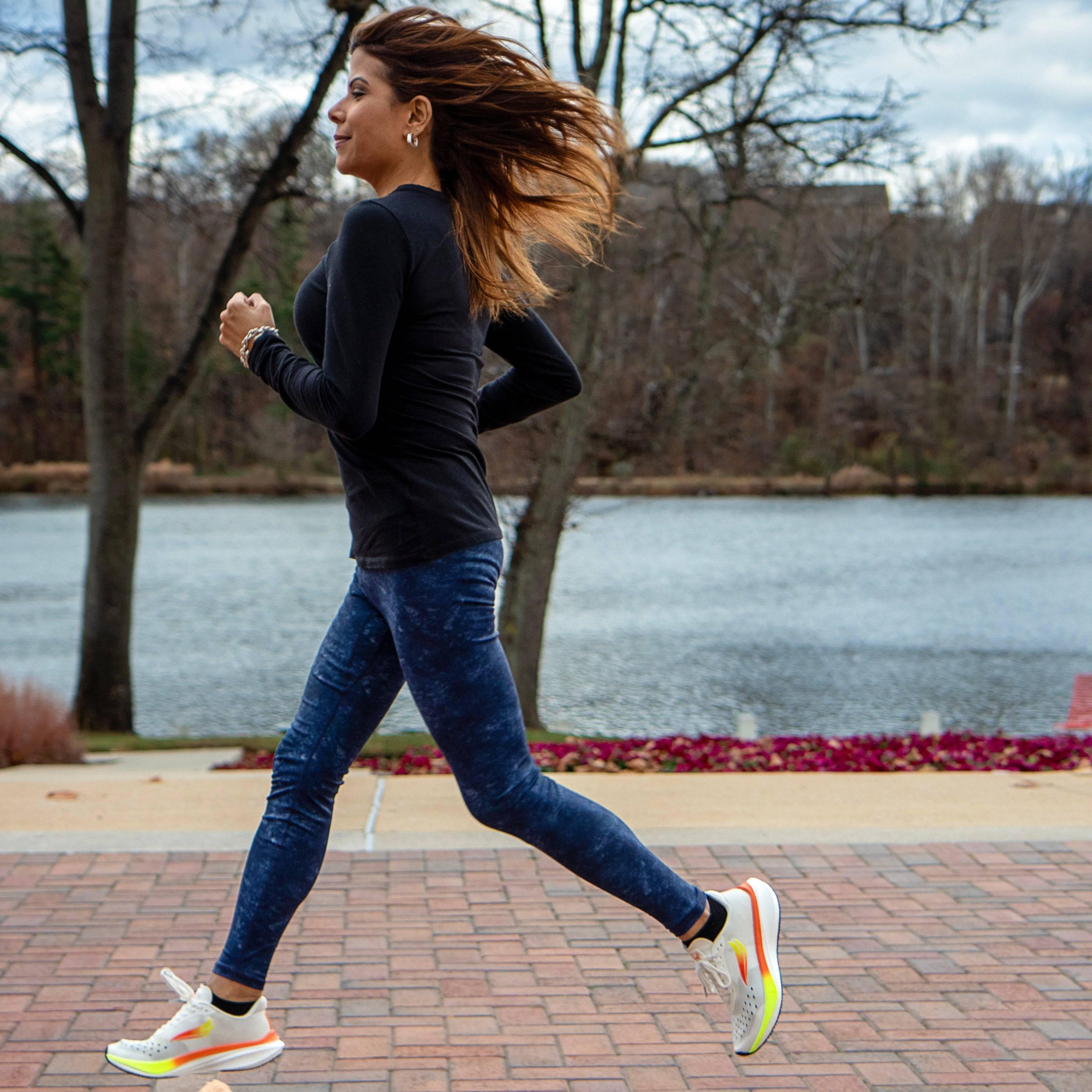 Woman running outdoors in athletic shoes on a brick path by a lake