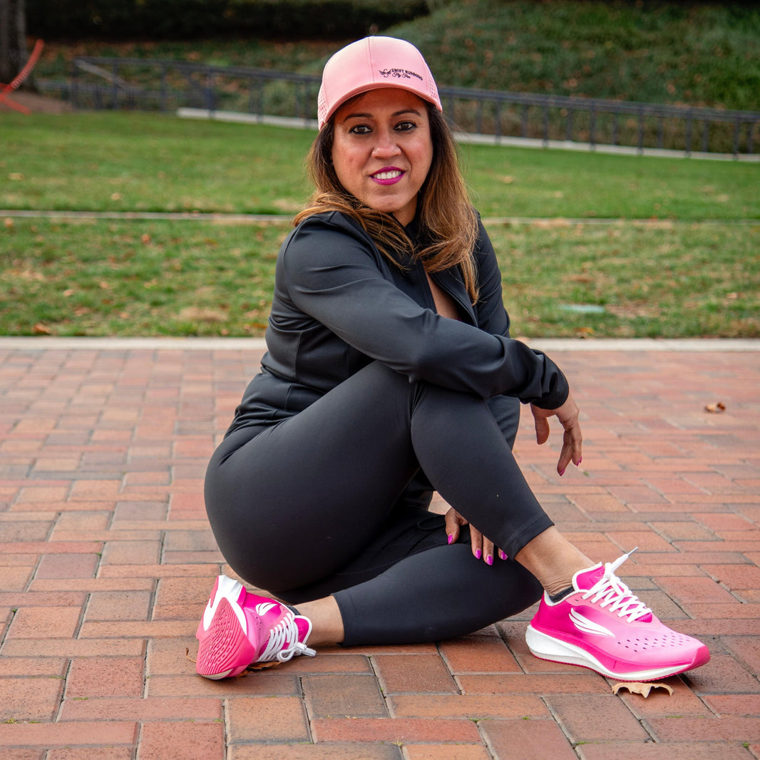 Woman sitting outdoors in pink running shoes and activewear on a brick path