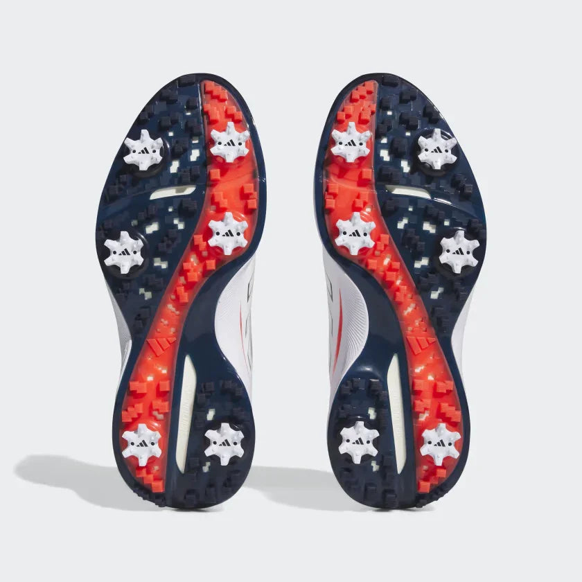 Pair of men's athletic golf shoes showing spiked soles with navy, red, and white grip design