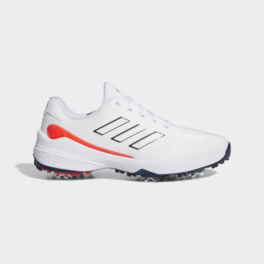 White men's golf shoe with black stripes, orange detail, spiked sole, side view