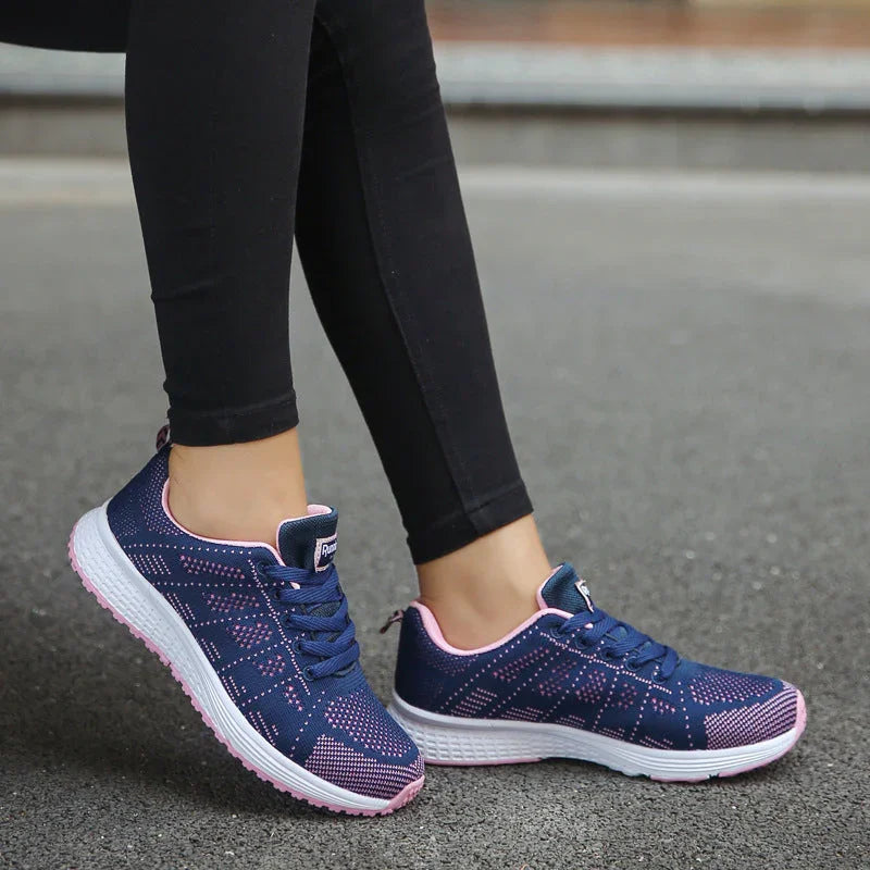 Woman wearing navy blue and pink athletic running shoes with white soles on pavement